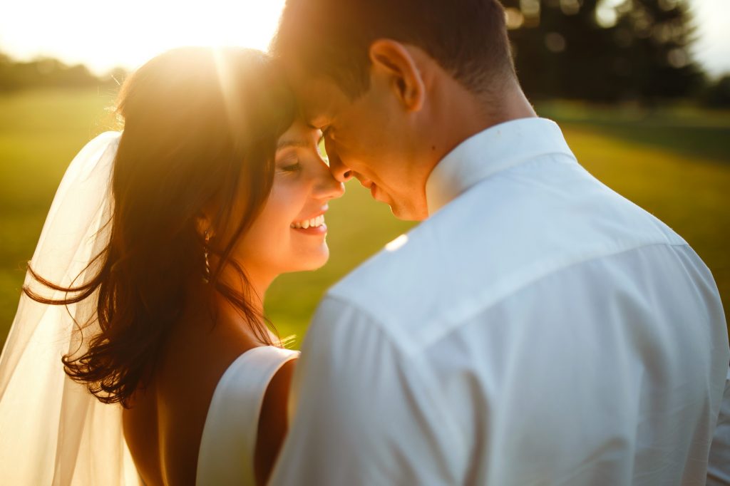 lovely wedding couple at sunset bride groom in wedding attire with bouquet of flowers romantic