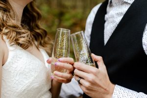 Closeup shot of the groom and bridge holding champagne glasses with the text sip hooray